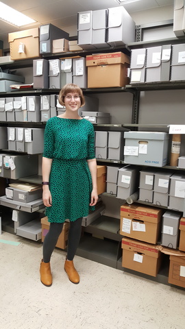 Anna Holland in front of shelves containing archival boxes